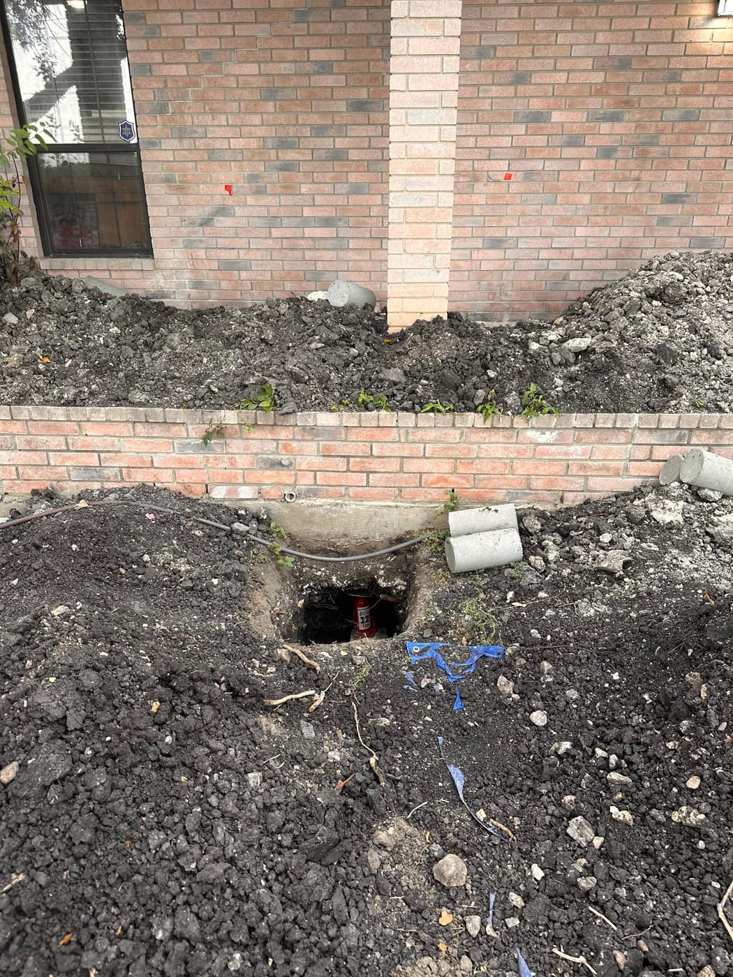 Drainage and concrete work along a brick foundation