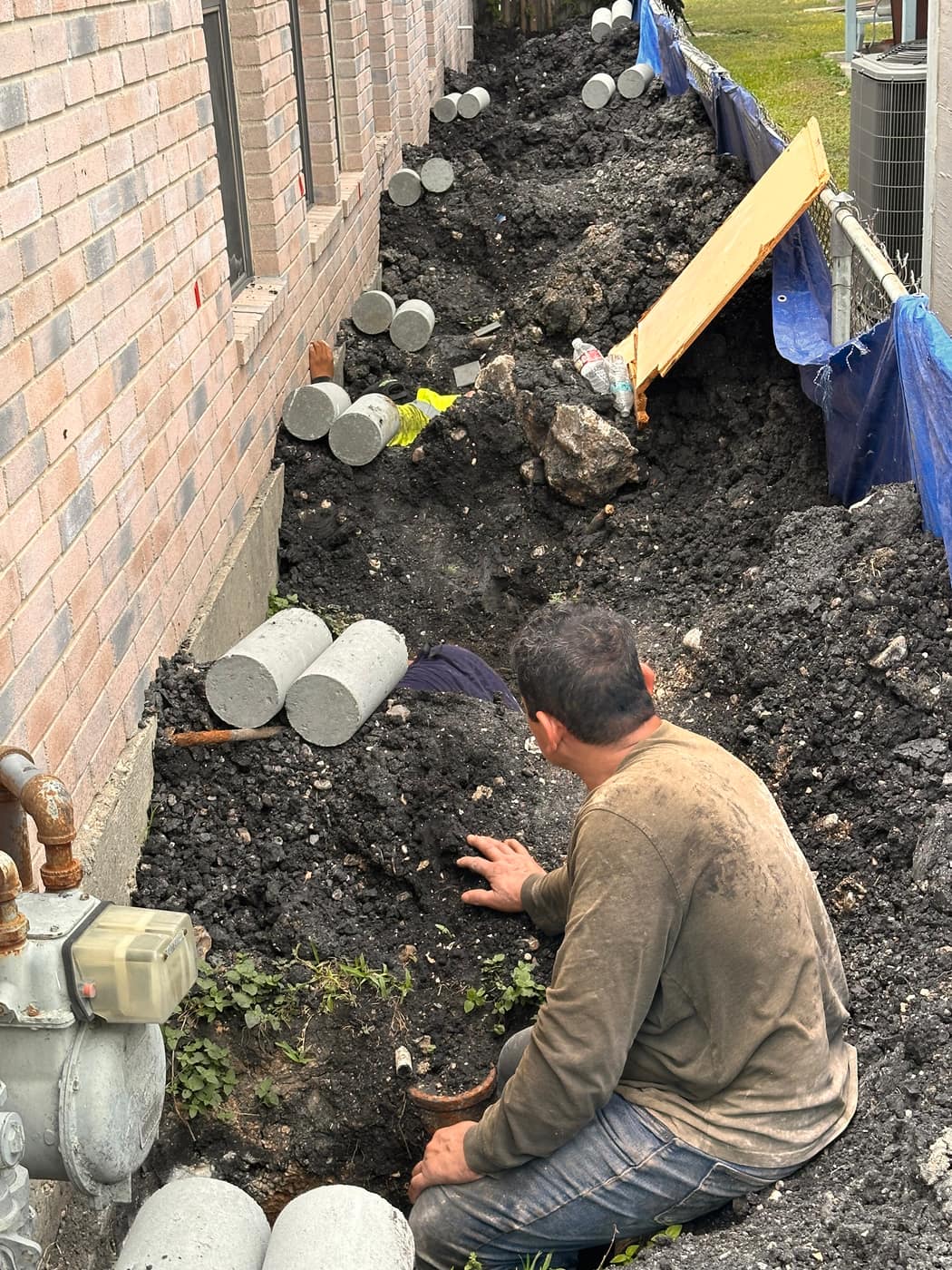 Worker installing foundation piers in a trench