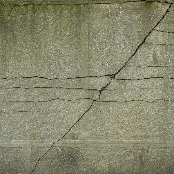 An image showing diagonal cracks in a wall near a window.